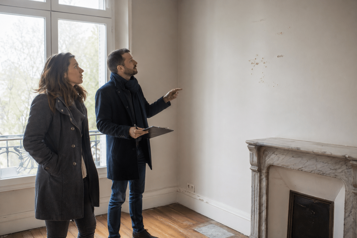 Deux personnes pointant un mur dans un appartement vide