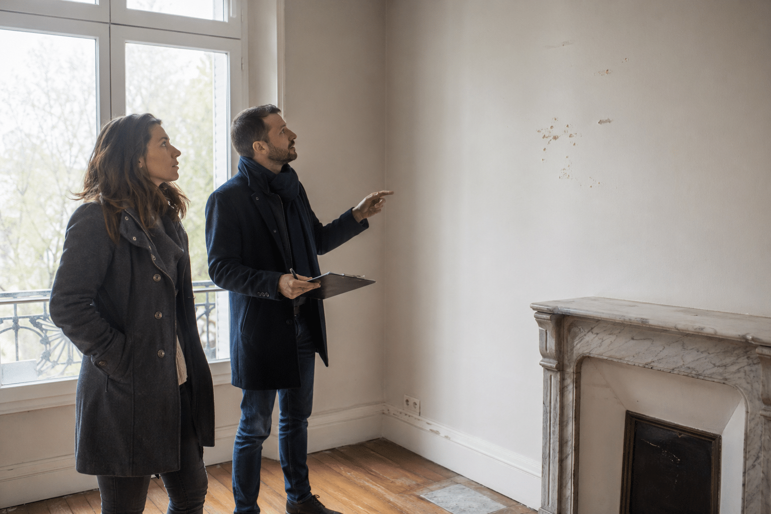 Deux personnes pointant un mur dans un appartement vide