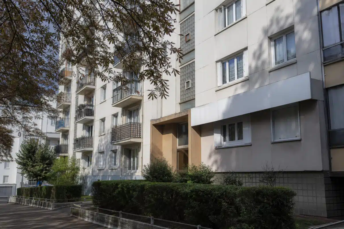 façade d'immeuble résidentiel avec balcons et haies