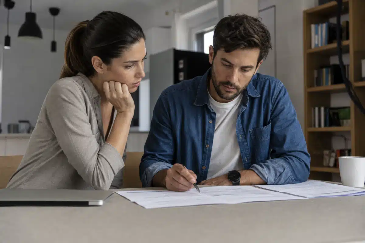 Homme écrivant sur des documents à table, femme l'observant