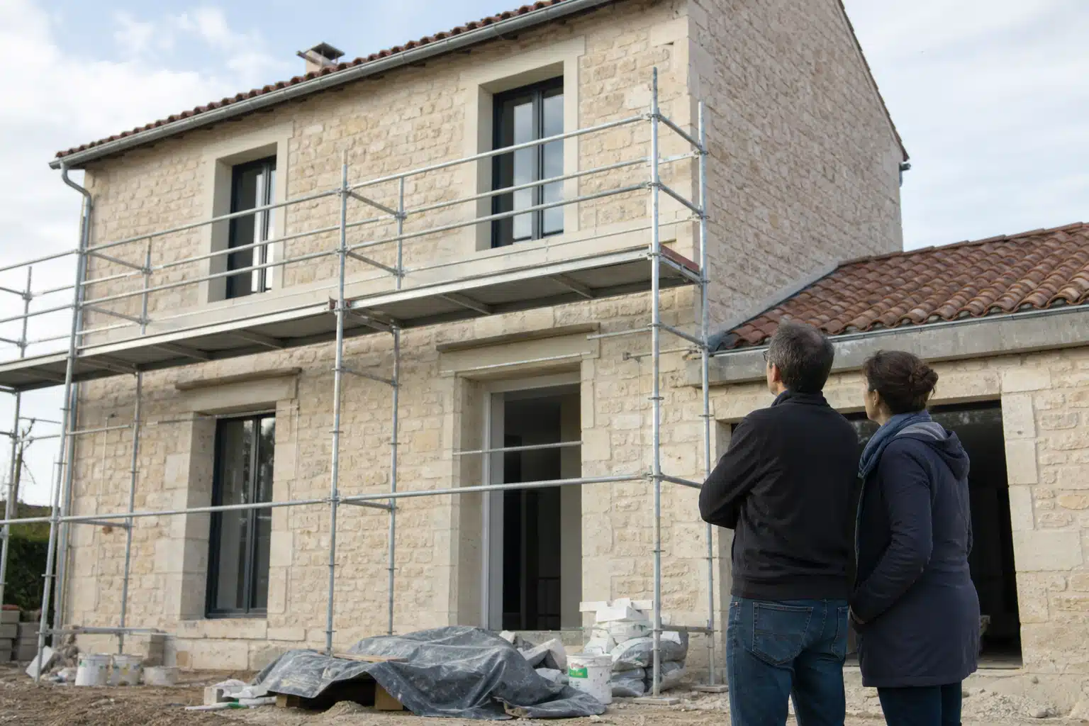 Deux personnes regardant échafaudage devant maison en rénovation